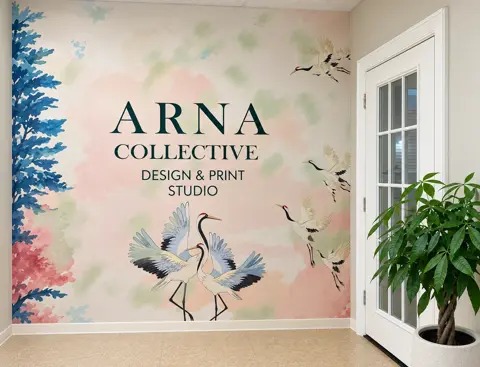 Interior wall with large printed Arna Collective lettering and a gold leaf motif above a console table